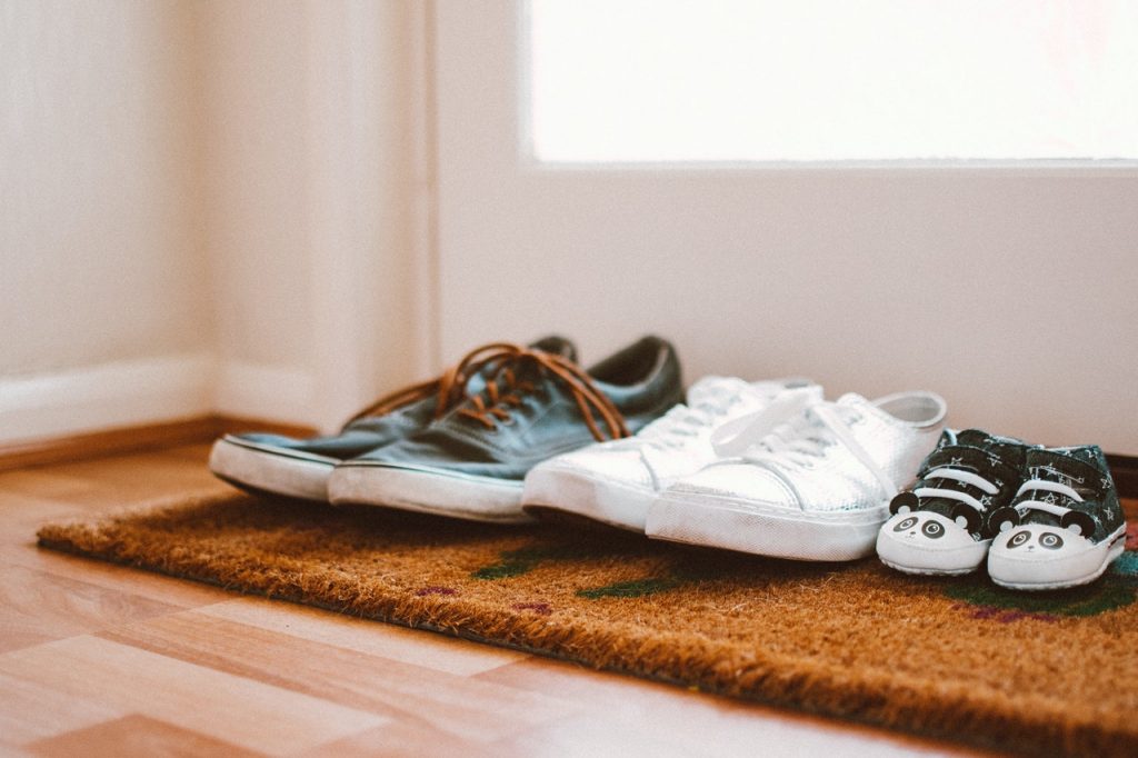 trois paires de chaussures posées sur un paillasson